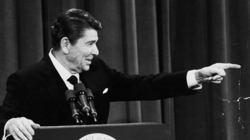 Ronald Reagan at a podium in Washington in 1982, pointing to his right while speaking.