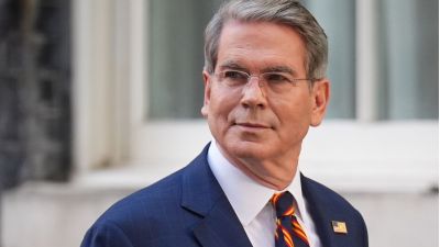 Scott Bessent, a man with gray hair and glasses, wearing a blue suit and striped tie, looking to the side.