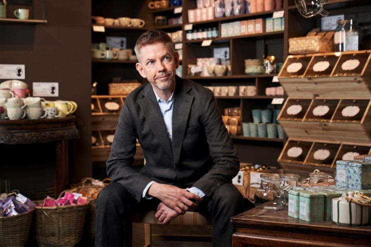 Man in suit seated in a Sostrene Grene store, surrounded by homeware and gift items.