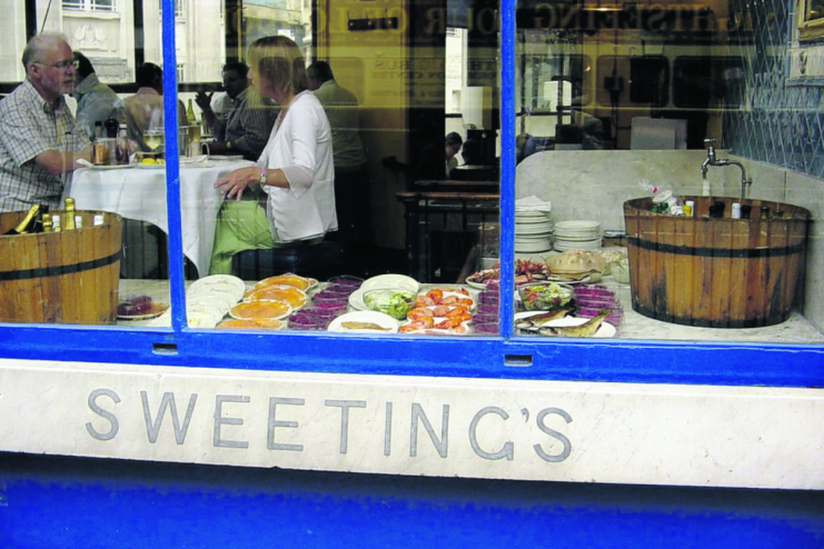 Sweetings City of London restaurant exterior, showing diners inside and a seafood display in the window.
