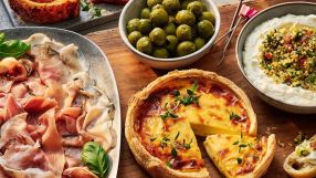 Tesco quiche, cured meats, olives, and dip on a wooden board, ready for a party or meal.