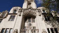 UK Supreme Court building, London, with intricate stone carvings and statues, under a blue sky