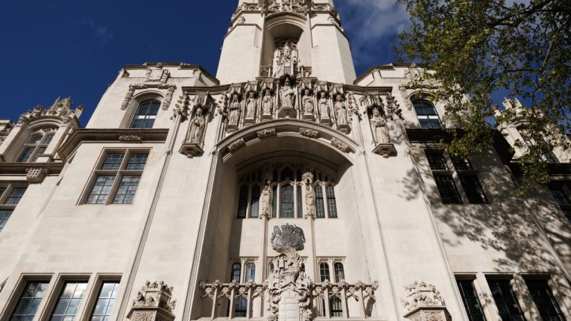UK Supreme Court building, London, with intricate stone carvings and statues, under a blue sky