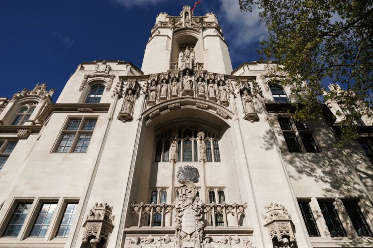 UK Supreme Court building, London, with intricate stone carvings and statues, under a blue sky