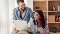 Happy couple shopping online with credit card and laptop, likely using CompleteSavings or similar service.