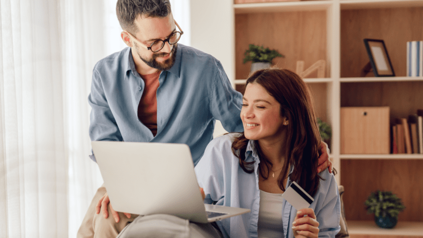 Happy couple shopping online with credit card and laptop, likely using CompleteSavings or similar service.
