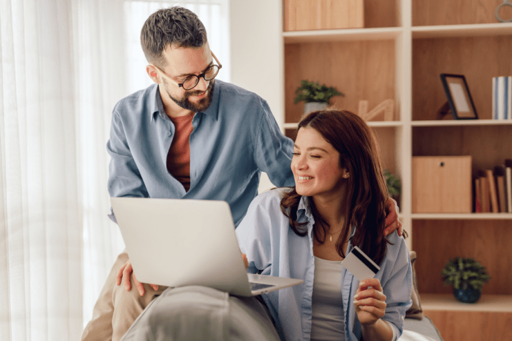 Happy couple shopping online with credit card and laptop, likely using CompleteSavings or similar service.