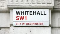 Whitehall SW1 street sign in the City of Westminster, London, mounted on a white stone wall with decorative trim.