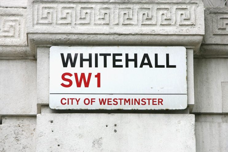 Whitehall SW1 street sign in the City of Westminster, London, mounted on a white stone wall with decorative trim.