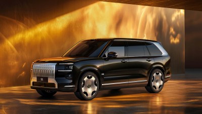 Dark brown Zeekr X9 electric MPV with large chrome grille, parked indoors with warm golden lighting.