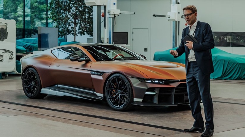 Aston Martin Vanquish Vision Concept with a man in a suit presenting it in a design studio.