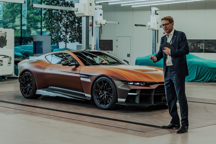 Aston Martin Vanquish Vision Concept with a man in a suit presenting it in a design studio.