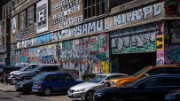 Vibrant graffiti art covering a brick building with parked cars in front, Truman Brewery area.