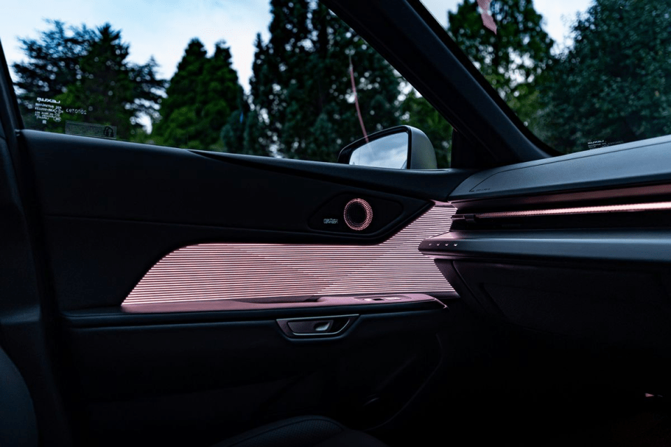Modern car interior with illuminated door panel and dashboard, showcasing ambient lighting and design details.