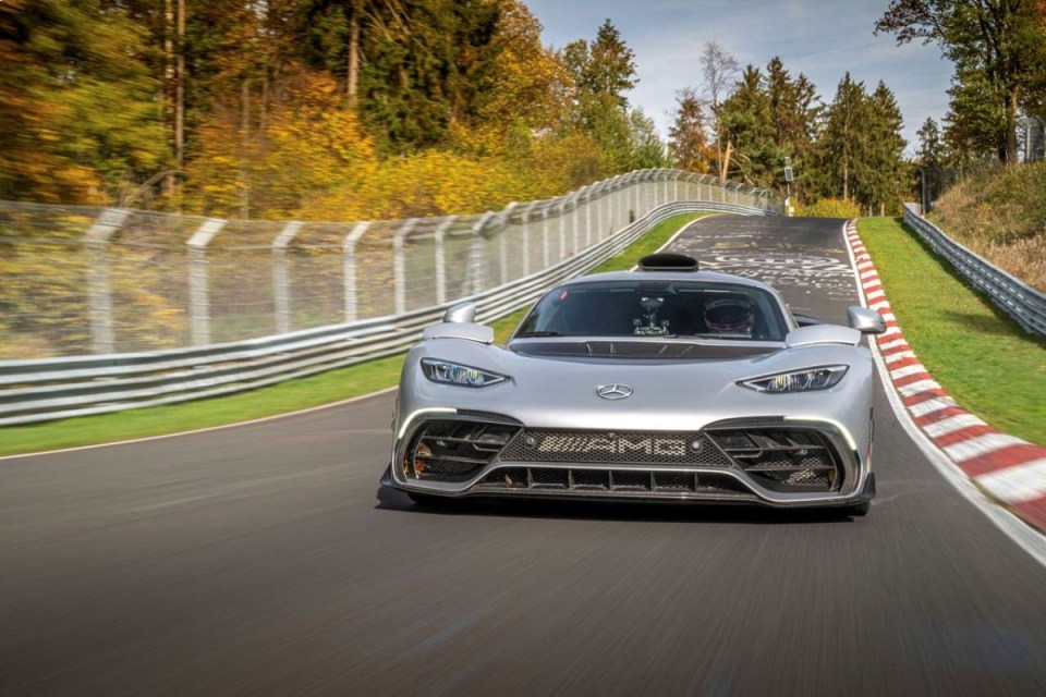 Silver Mercedes-AMG ONE hypercar on a race track with autumn trees in the background