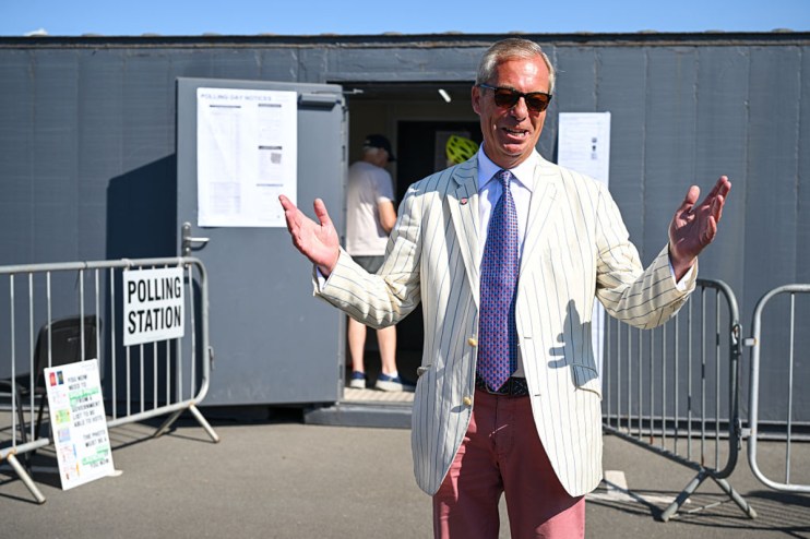 Nigel Farage, in a striped jacket and sunglasses, speaks outside a polling station.