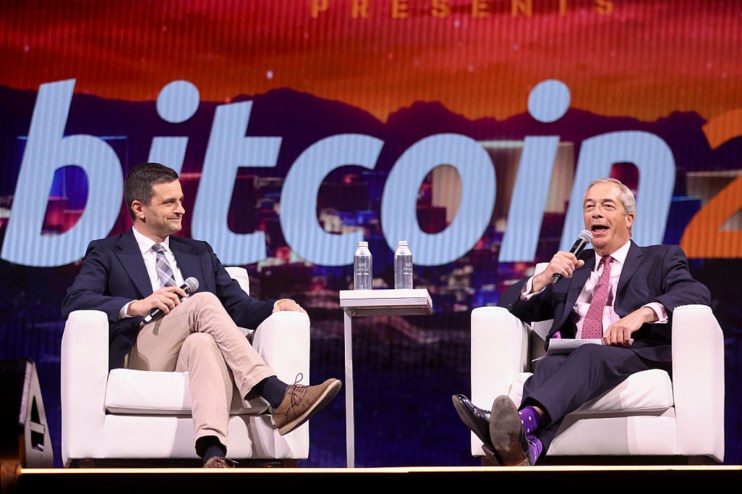 Nigel Farage and another man on stage discussing crypto and UK reform, with Bitcoin on screen.