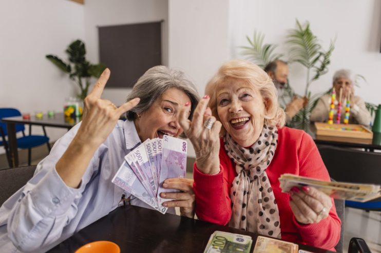 Two joyful senior women holding Euro banknotes, celebrating financial freedom and successful retirement planning