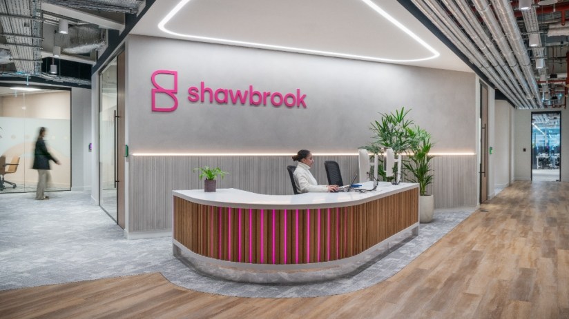 Shawbrook Bank reception desk with a woman working, modern office interior with shawbrook logo on wall, Ledenhall Street l...
