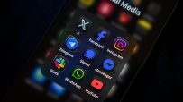 Smartphone screen displaying a folder of social media app icons including Facebook, Instagram, WhatsApp, and YouTube.