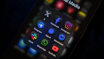 Smartphone screen displaying a folder of social media app icons including Facebook, Instagram, WhatsApp, and YouTube.