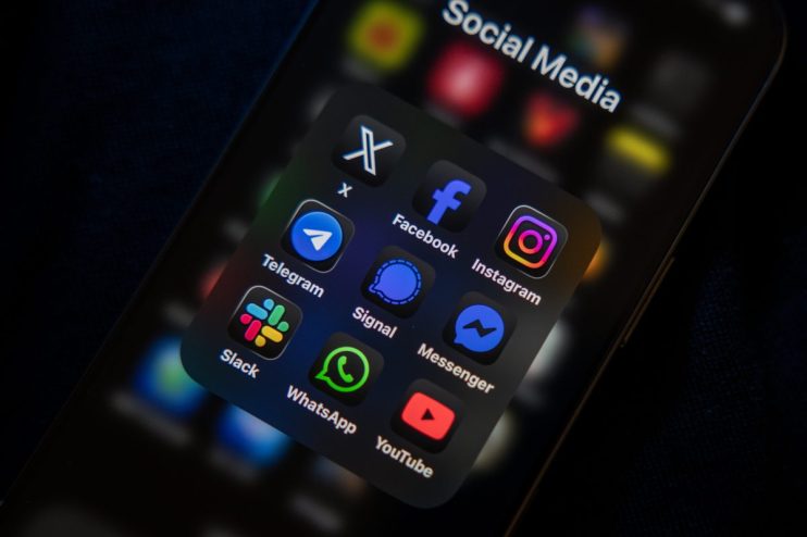 Smartphone screen displaying a folder of social media app icons including Facebook, Instagram, WhatsApp, and YouTube.