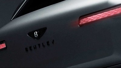 Close-up of a matte dark grey Bentley car with a B logo and red taillights