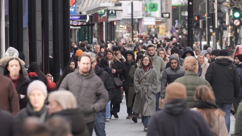 Crowd of people walking on a busy city street with shops and traffic lights in the background