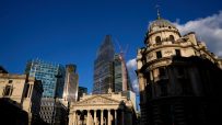City of London skyline with historic buildings, modern skyscrapers, and construction cranes under blue sky.