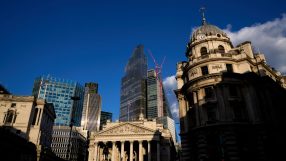 City of London skyline with historic buildings, modern skyscrapers, and construction cranes under blue sky.