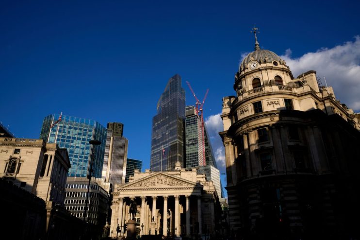 City of London skyline with historic buildings, modern skyscrapers, and construction cranes under blue sky.