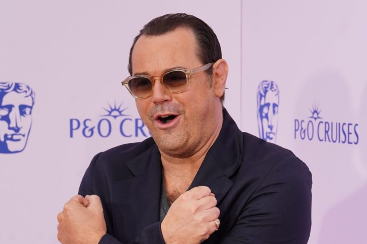 James Corden in sunglasses on a purple background with P&O Cruises and BAFTA logos visible, arms crossed.