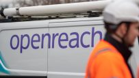 Openreach van with a white roof rack and a worker in an orange high-visibility jacket and white hard hat
