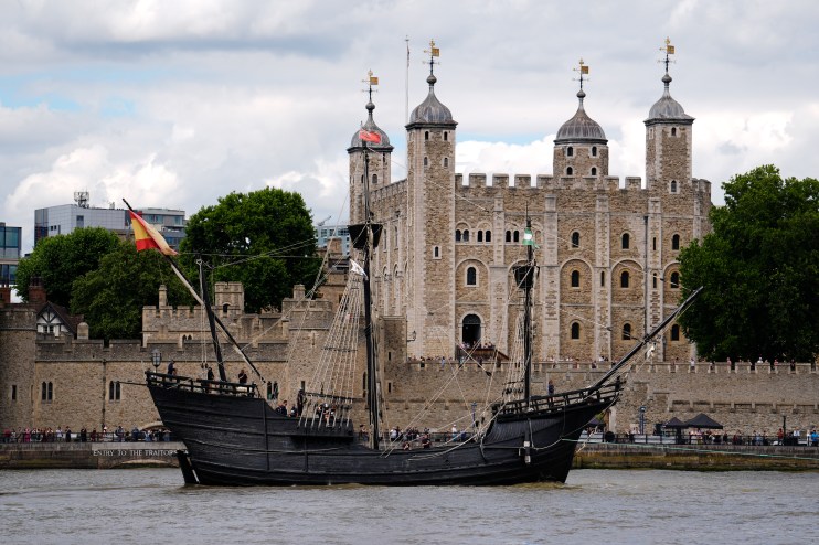 A replica historic sailing ship with a Spanish flag on the Thames River in front of the Tower of London