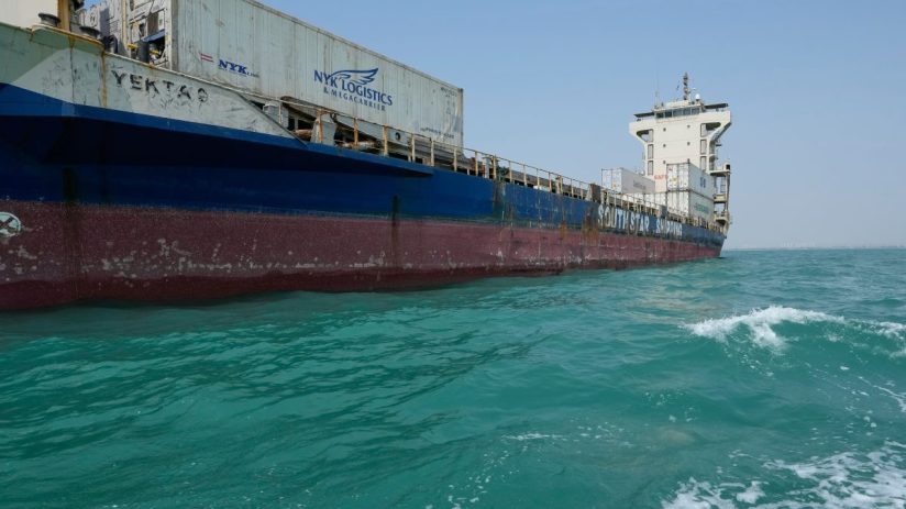 Cargo ship YEKTA 9 with NYK Logistics containers on turquoise water, clear sky. Maritime transport.