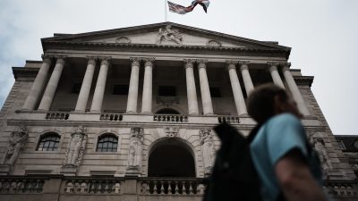 Bank of England building with a Union Jack flag flying, seen from below, a person in foreground