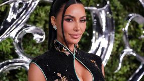 Kim Kardashian in a black sequined dress with a mandarin collar, diamond earrings, and a sleek ponytail.