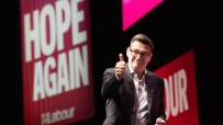 Andy Burnham, Mayor of Greater Manchester, gives a thumbs-up gesture in front of a Hope Again Labour banner.