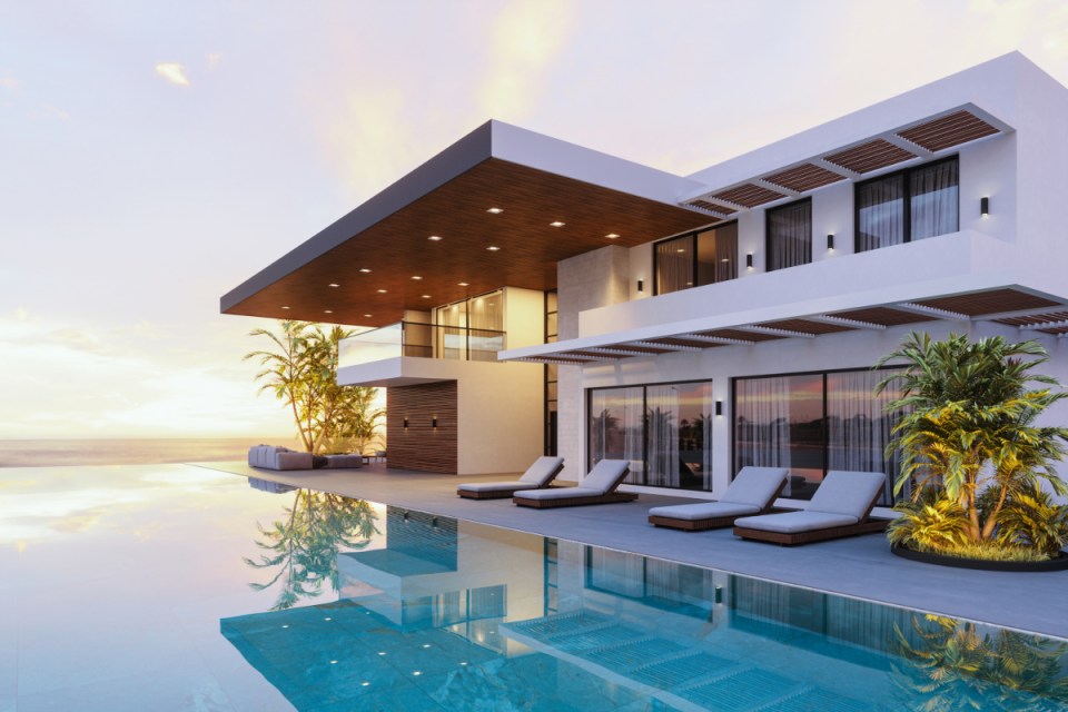 Modern luxury villa with infinity pool overlooking ocean at sunset