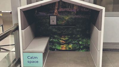 Calm Space booth with a nature mural and light grey bench, offering a quiet retreat in a public area.