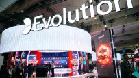 Evolution Gaming booth with illuminated signage and screens showcasing casino games at a busy industry event.