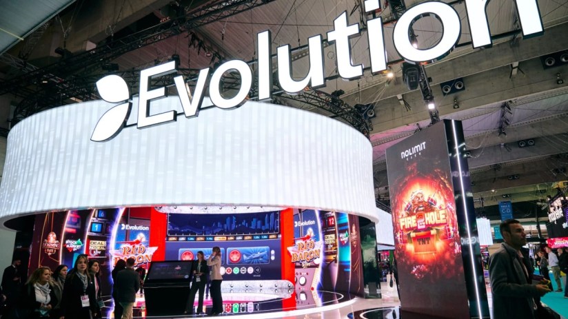 Evolution Gaming booth with illuminated signage and screens showcasing casino games at a busy industry event.