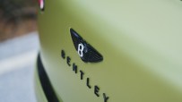 Close-up of a matte olive green Bentley cars rear with the black winged B logo and BENTLEY lettering