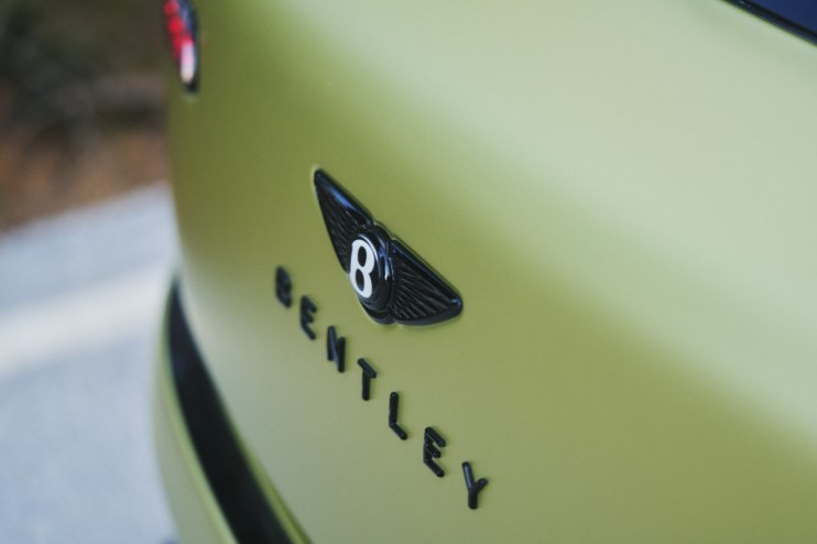 Close-up of a matte olive green Bentley cars rear with the black winged B logo and BENTLEY lettering