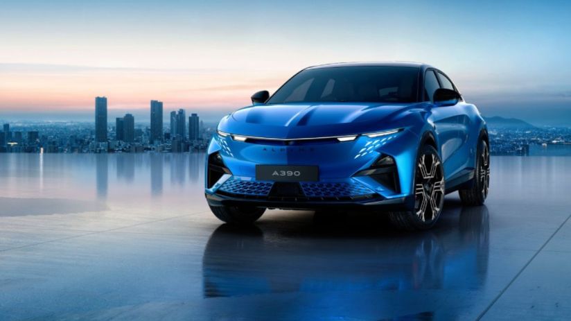 Sleek blue Alpine A390 electric SUV with distinctive headlights, parked on a reflective surface before a city skyline at d...