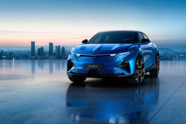 Sleek blue Alpine A390 electric SUV with distinctive headlights, parked on a reflective surface before a city skyline at d...