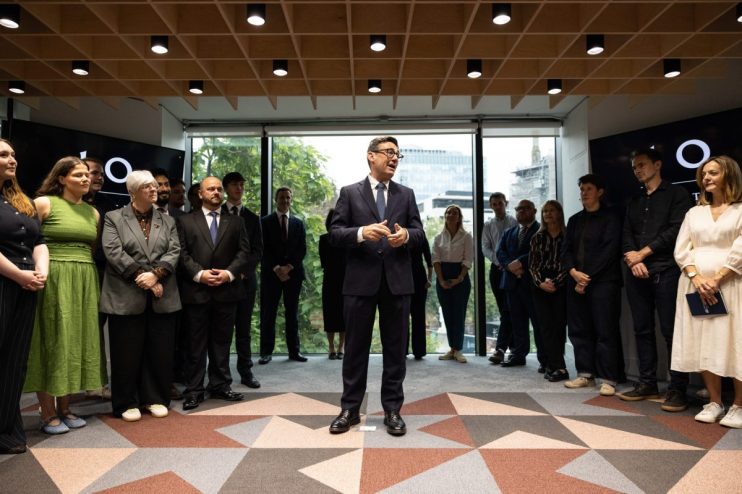 Andy Burnham speaking at Number 10 North, surrounded by a diverse group of attendees in a modern office setting.