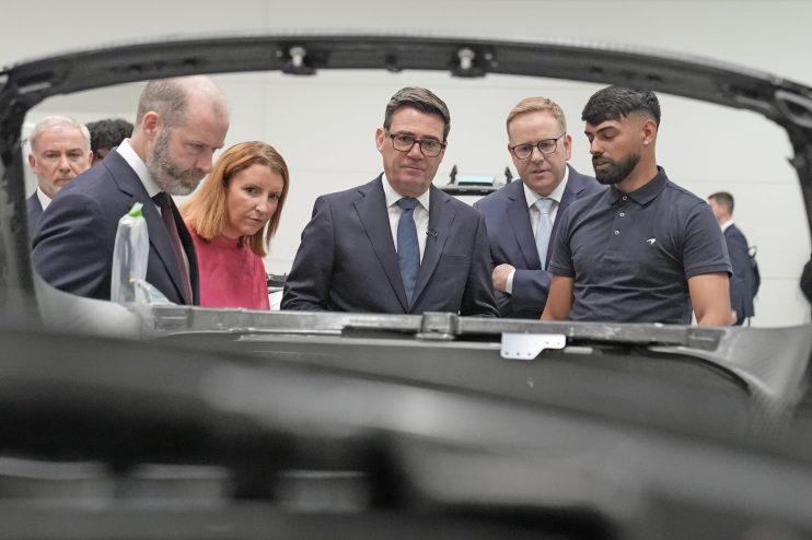Andy Burnham and others inspecting a manufacturing process, likely at a Labour Party conference related event.