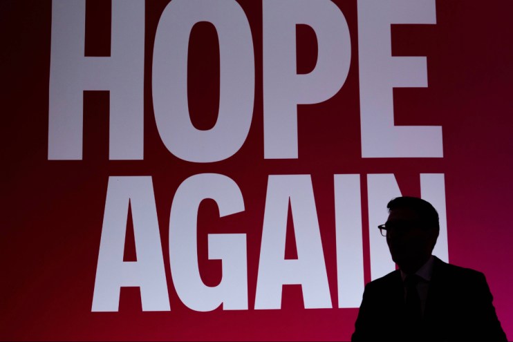 Silhouette of Andy Burnham speaking, with HOPE AGAIN text in white on a red background behind him.