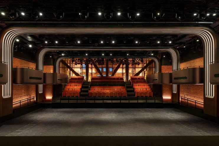 Interior of a modern music venue in London with a stage, tiered seating, and architectural lighting.